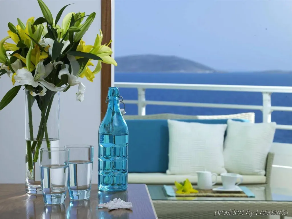 Une table avec des fleurs et des verres donne sur une vue mer depuis une terrasse.