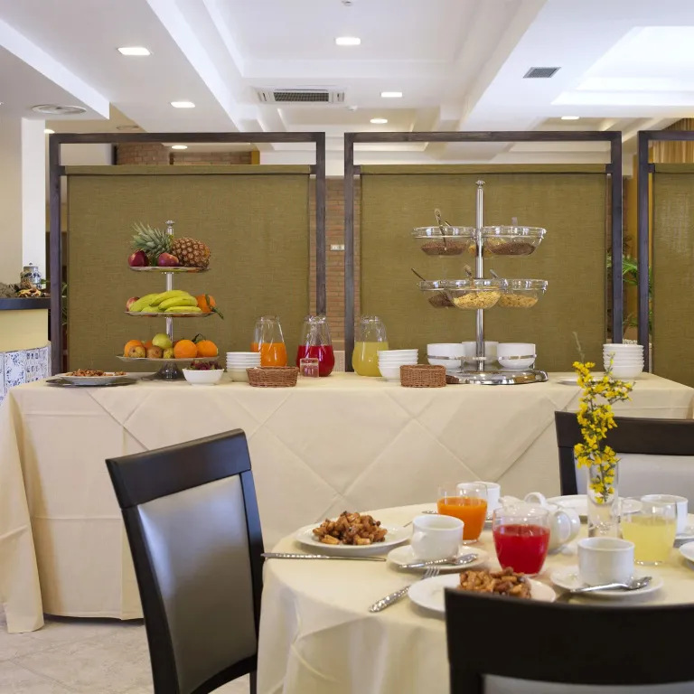 Une table est dressée avec des céréales, des jus de fruits et du café.