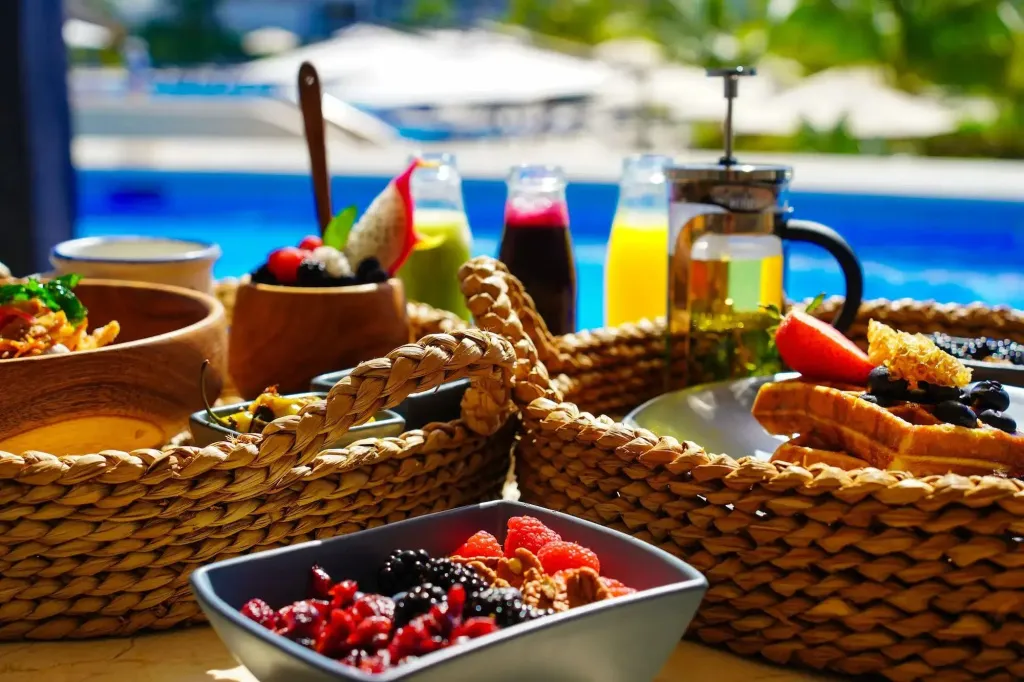 Un buffet de petit-déjeuner coloré est présenté au bord d'une piscine.