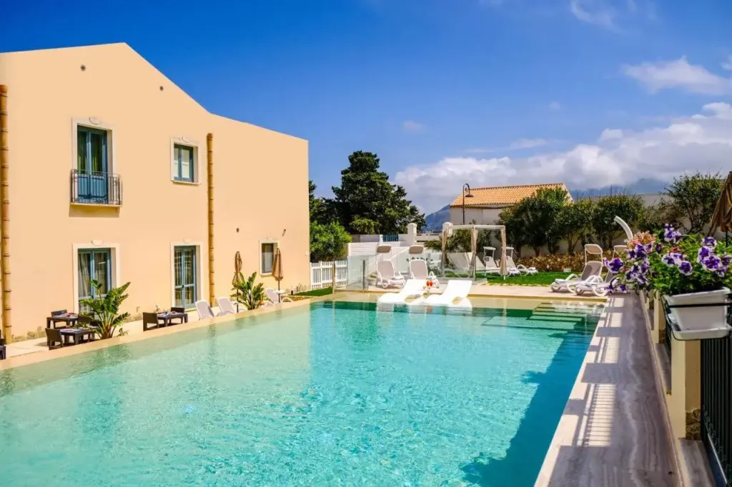 Une piscine rectangulaire bordée de transats et d'une terrasse ensoleillée.