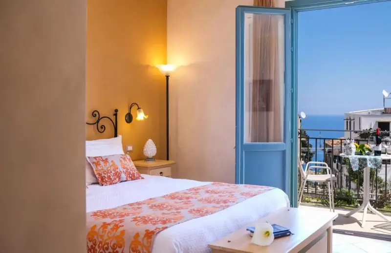 Une chambre lumineuse s'ouvre sur un balcon avec vue sur la mer.