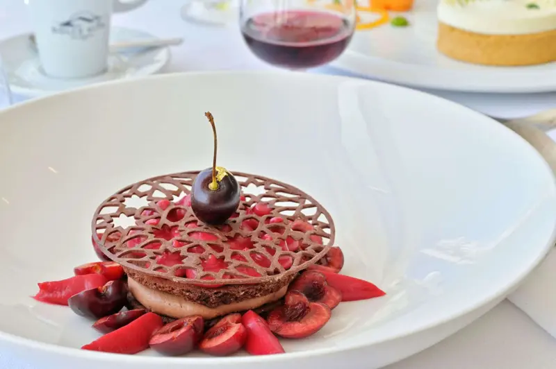 Un dessert au chocolat et aux cerises est présenté sur une assiette blanche.