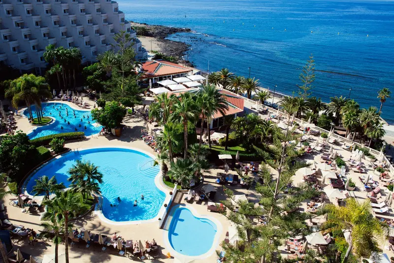 Vue aérienne sur un complexe hôtelier avec piscines et accès à la mer.