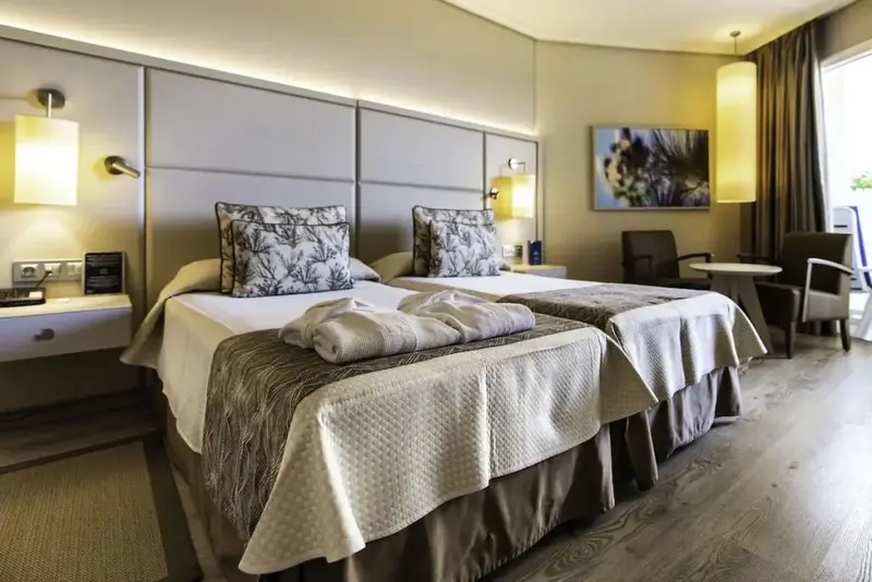 Une chambre lumineuse avec deux lits simples et un coin salon.