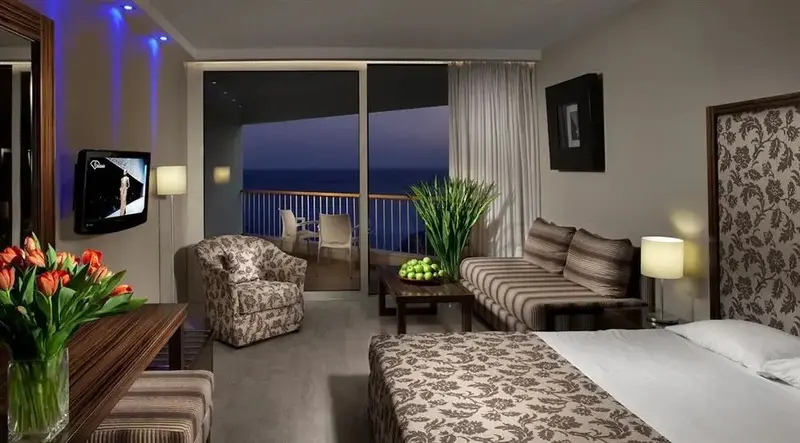 Une chambre lumineuse s'ouvre sur un balcon avec vue sur la mer.