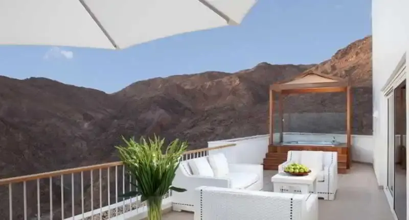 Terrasse aménagée avec mobilier blanc et vue sur un paysage montagneux.