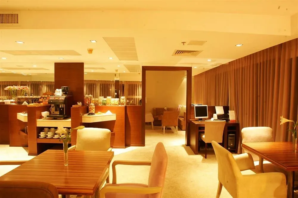 Une salle lumineuse avec des tables et des chaises, un buffet de petit-déjeuner et un coin informatique.