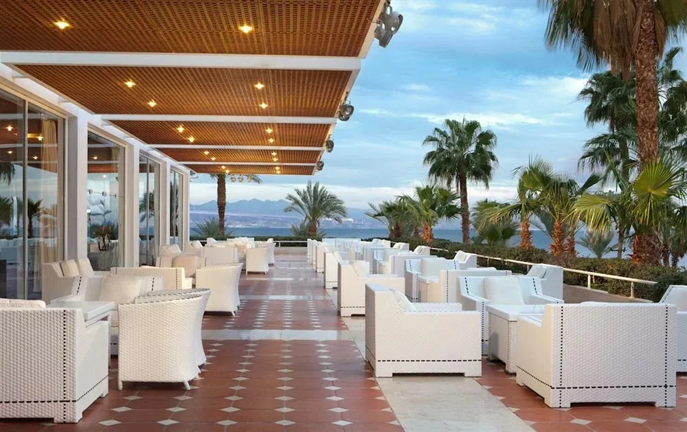 Espace de détente extérieur avec mobilier blanc et vue sur la mer.