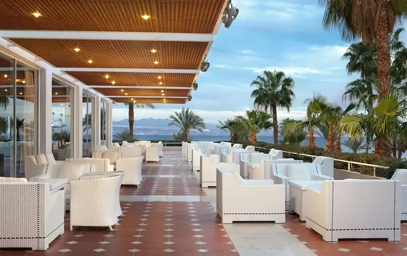 Espace de détente extérieur avec mobilier blanc et vue sur la mer.
