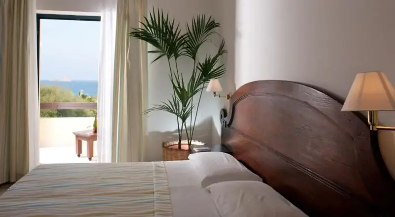 Une chambre lumineuse s'ouvre sur une vue mer par une baie vitrée.