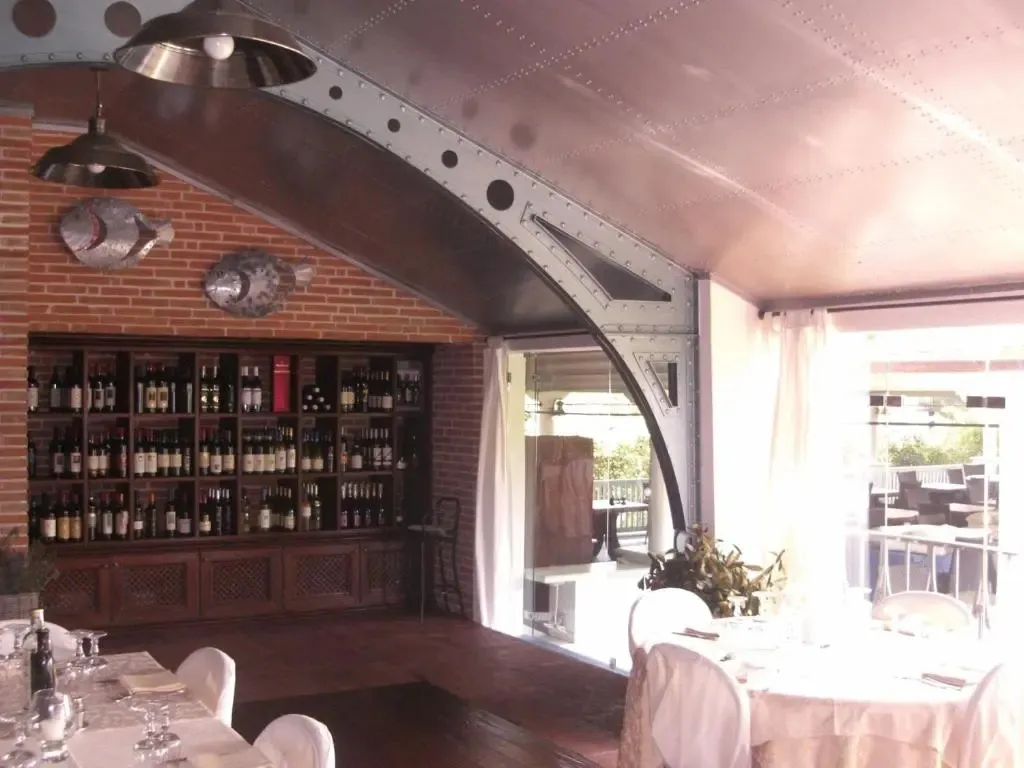 Une salle lumineuse avec des tables nappées et un bar bien garni en bouteilles.