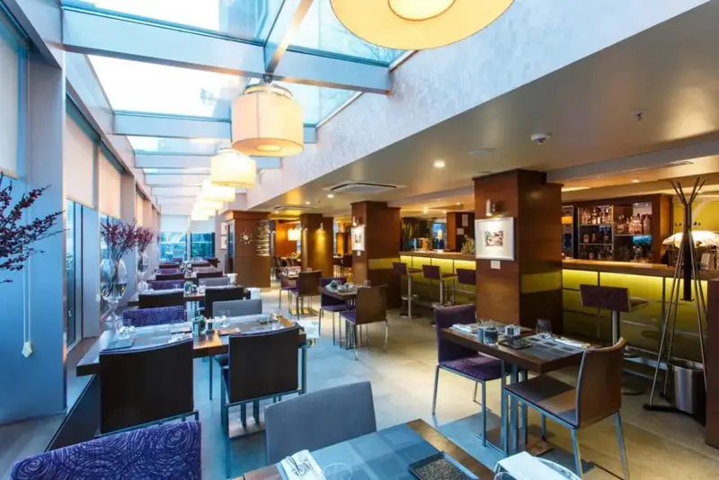 Une salle lumineuse avec des tables dressées et un comptoir de bar.