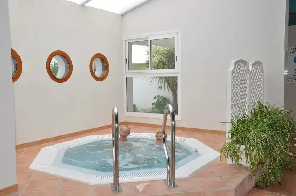 Deux personnes se détendent dans un jacuzzi intérieur lumineux.