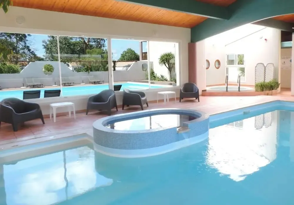 Une piscine intérieure avec des transats et un jacuzzi.