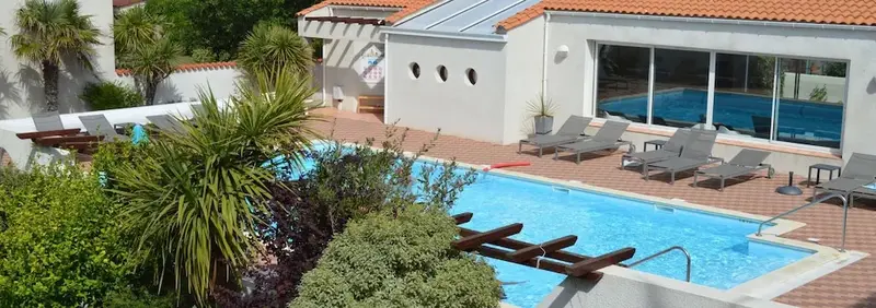 Piscine extérieure avec transats et végétation luxuriante.