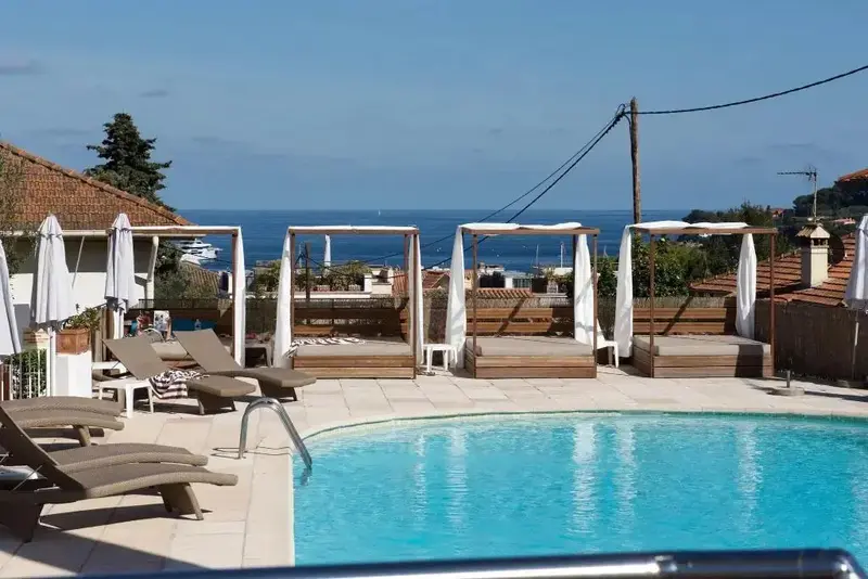 Transats et parasols bordent une piscine avec vue sur la mer.