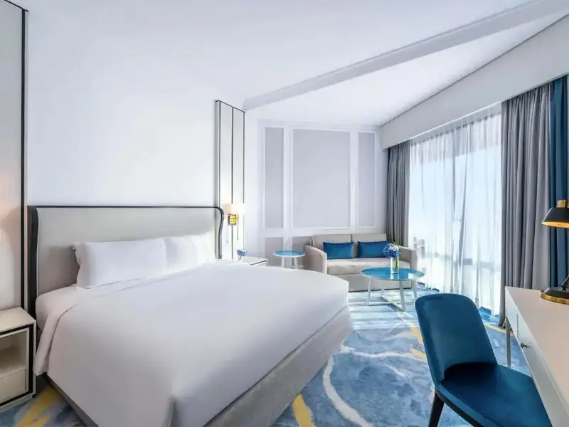 Une chambre lumineuse avec un grand lit et un coin salon.