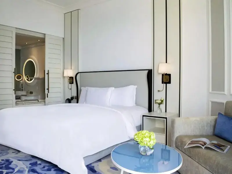 Une chambre lumineuse avec un grand lit et un coin salon.