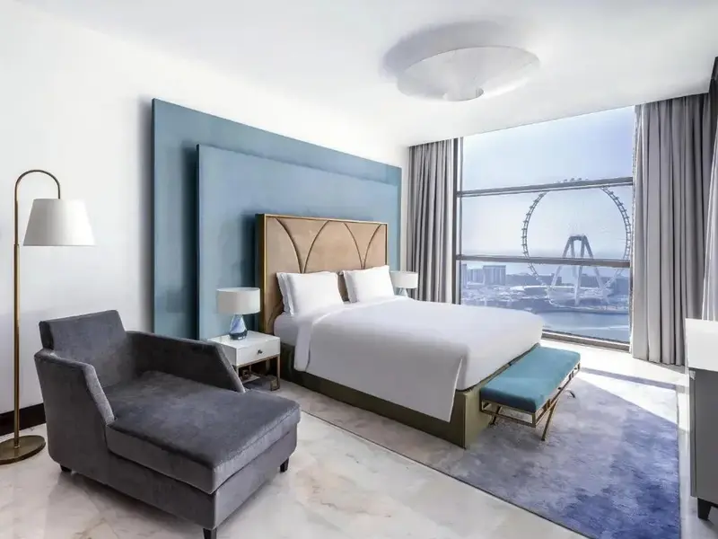 Une chambre lumineuse avec un grand lit et un fauteuil.