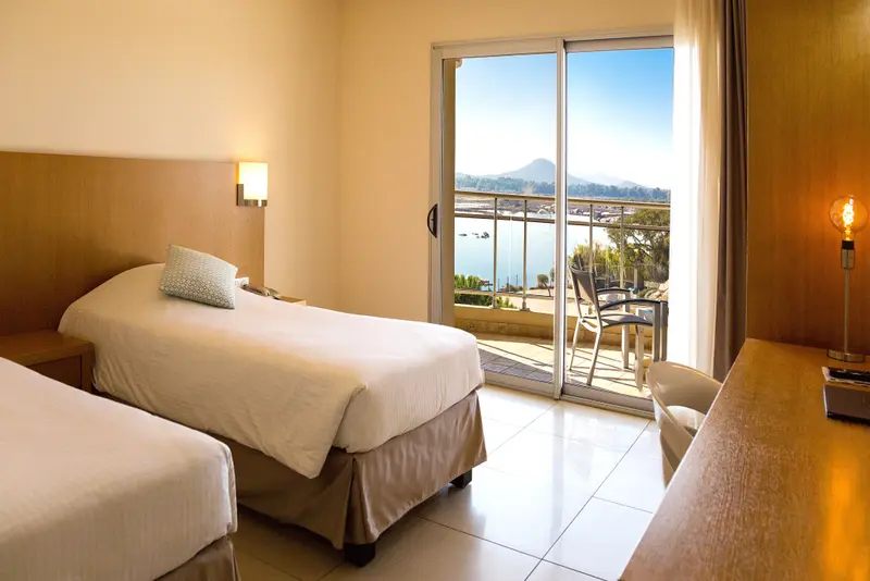 Chambre lumineuse avec vue sur la mer depuis une baie vitrée.