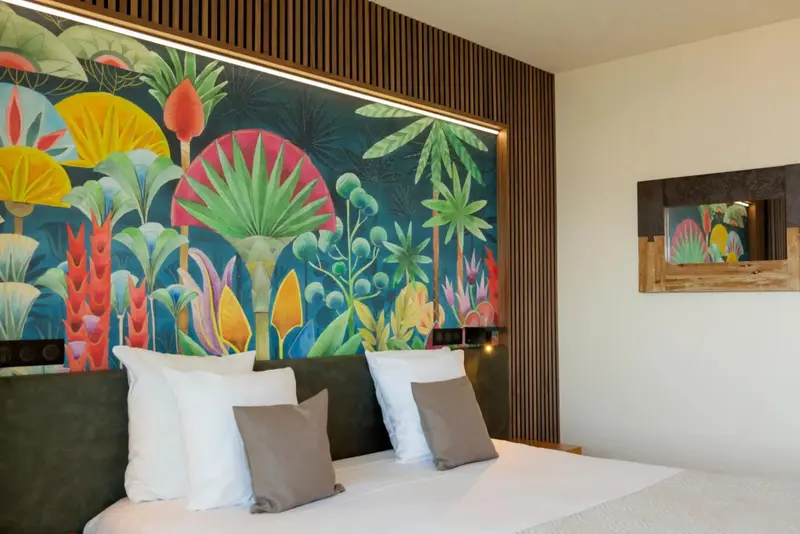Une chambre lumineuse avec un grand décor floral mural au-dessus du lit.
