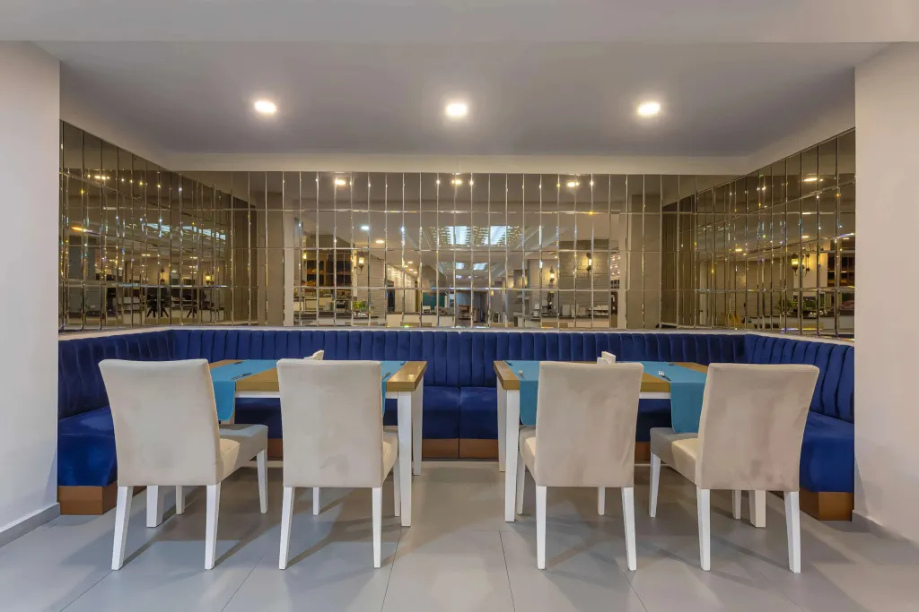 Une salle lumineuse avec des tables et des banquettes bleues.