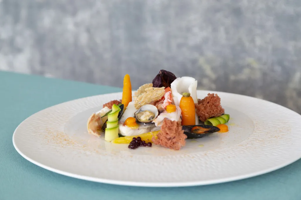 Assiette de fruits de mer et de légumes disposés avec soin.