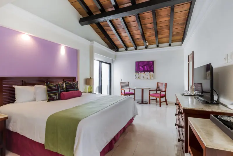 Une chambre lumineuse avec un grand lit et un coin repas.