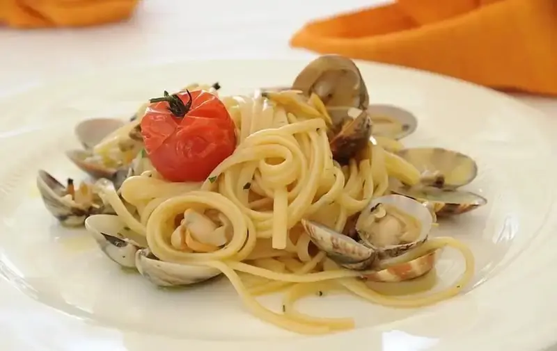 Assiette de spaghetti aux palourdes décorée d'une tomate cerise.