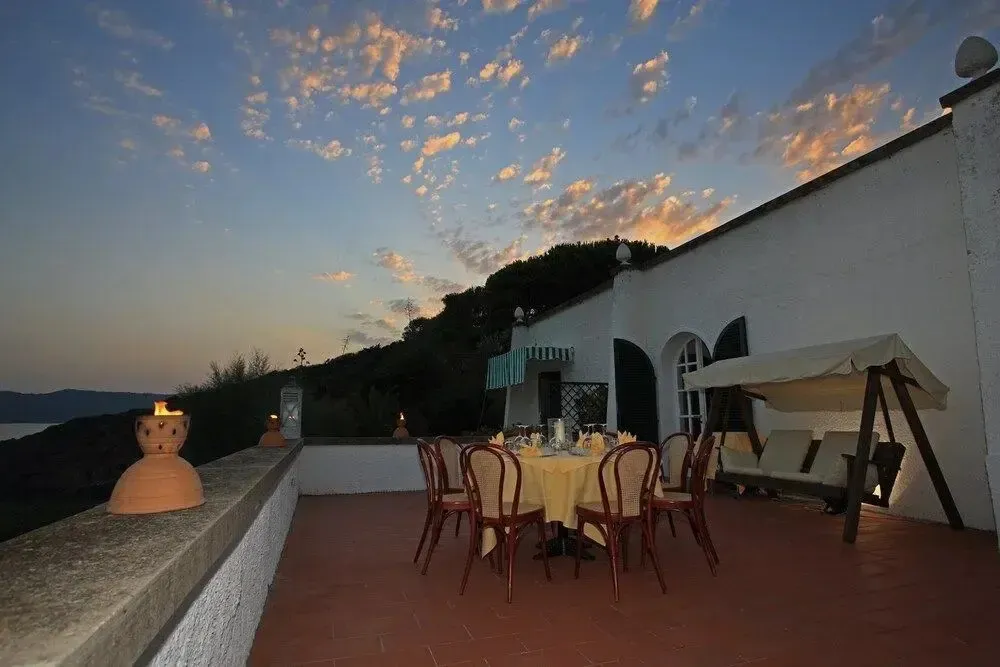Table dressée sur une terrasse avec vue sur la mer au coucher du soleil.