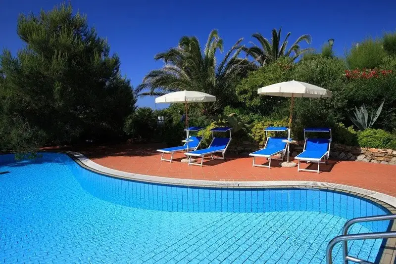 Transats bleus et parasols blancs bordent une piscine carrelée d'azur.