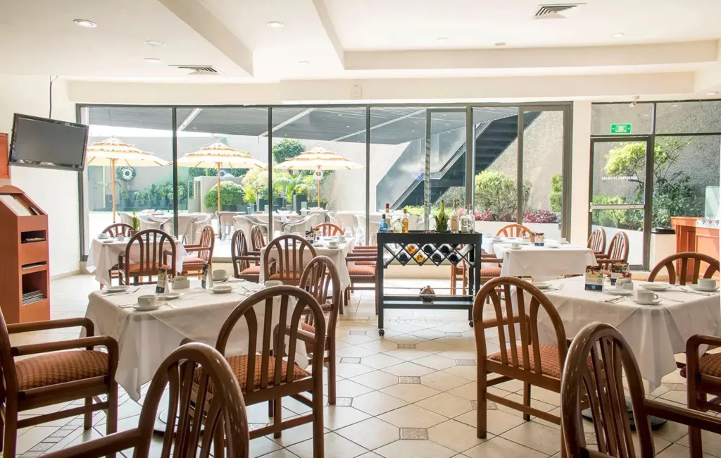 Une salle lumineuse avec des tables dressées pour le repas.