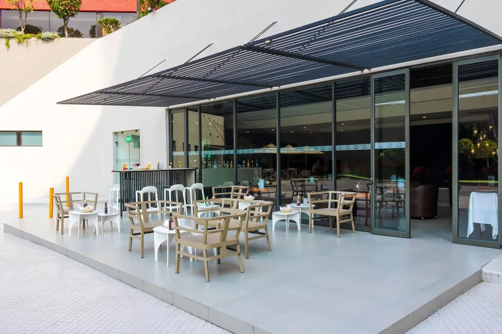 Espace extérieur ombragé avec tables et un comptoir de bar.