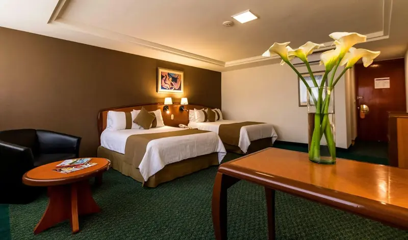 Chambre avec deux lits et un vase de fleurs.