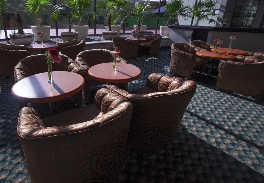 Espace de détente avec des fauteuils et des tables basses ornées de fleurs.