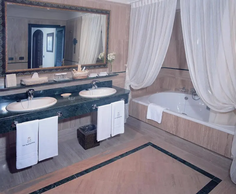 Une salle de bain lumineuse avec une double vasque et une baignoire.