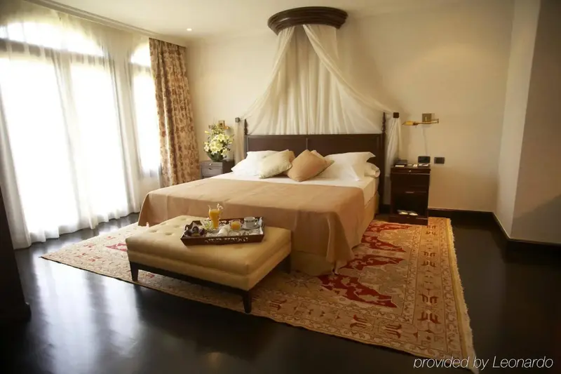 Une chambre spacieuse avec un grand lit à baldaquin et un plateau de petit-déjeuner.