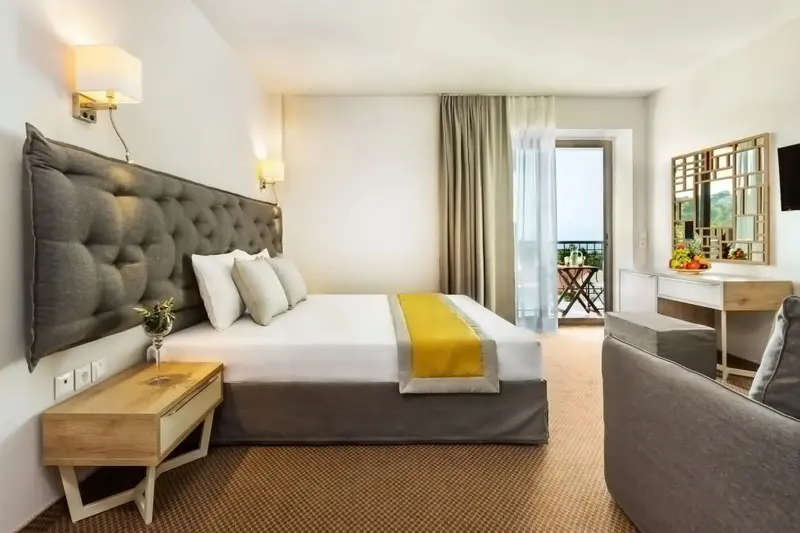 Une chambre lumineuse avec un grand lit et un accès à un balcon.