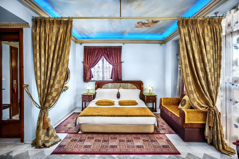Une chambre à coucher lumineuse avec un lit à baldaquin et des rideaux dorés.