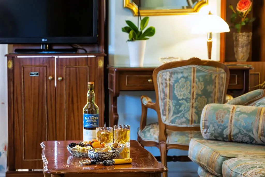 Une table basse avec une bouteille et des verres se trouve devant un canapé et un fauteuil.