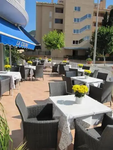 Tables et chaises disposées en extérieur sous un auvent bleu.