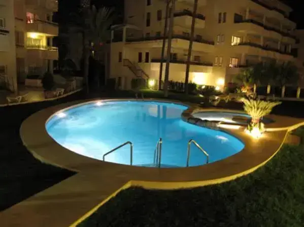Piscine illuminée au sein d'un complexe hôtelier la nuit.