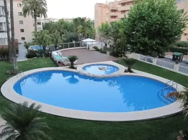 Piscine extérieure avec terrasse ensoleillée et végétation luxuriante.