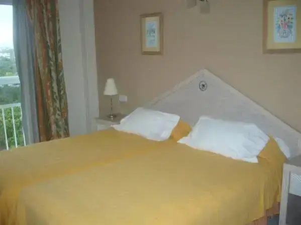 Une chambre lumineuse avec un grand lit recouvert d'une courtepointe jaune.
