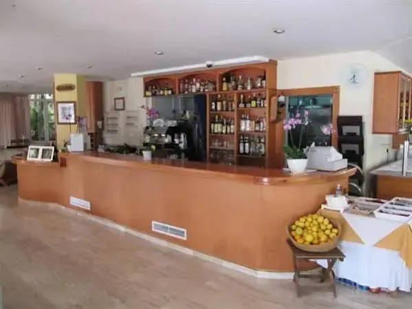 Un comptoir de bar en bois clair est présenté avec une variété de bouteilles et de verres.