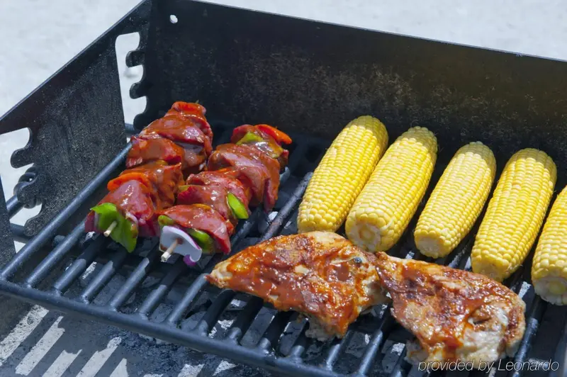Brochettes de viande et maïs grillés sur un barbecue.
