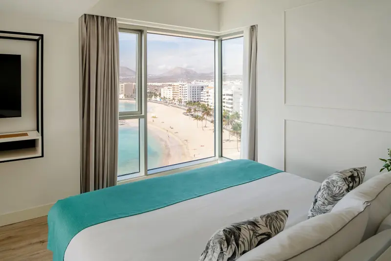 Une chambre lumineuse offre une vue dégagée sur la plage et la mer.