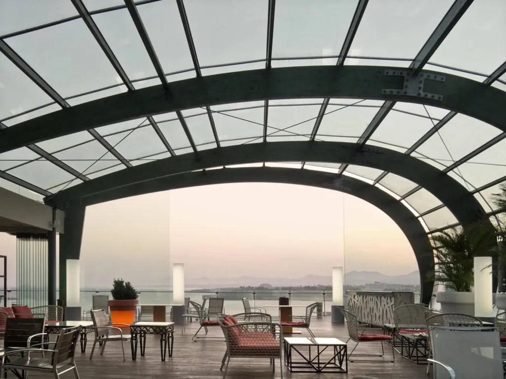 Terrasse ombragée avec mobilier de jardin et vue sur la mer.