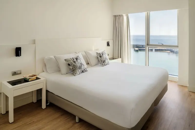 Une chambre lumineuse avec un grand lit et une vue sur la mer.
