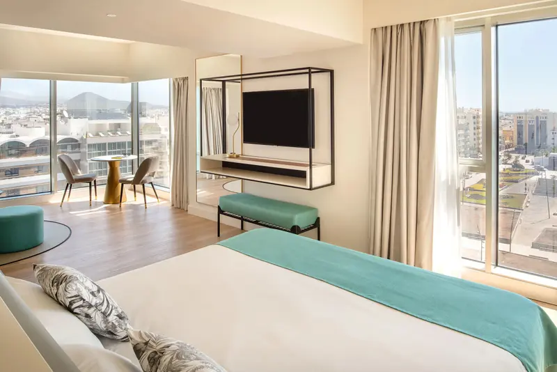 Une chambre lumineuse avec un grand lit et une vue sur la ville.
